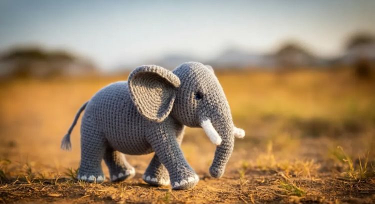 Imagen creada con Image3 AI de Google bajo el mensaje "Elefante amigurumi caminando por la sabana, una fotografía profesional, fondo borroso".